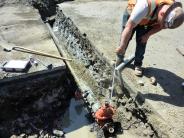 Contractor works on water line running through trench in St. Helens