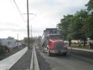 Construction work and equipment on road with unpaved road and new sidewalks installed