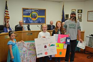 Participants of the poster contest standing with their posters with Mayor Rick Scholl 
