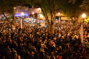 Night time festival crowd in plaza around giant pumpkin