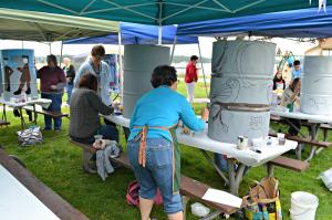 People painting artwork on grey trash cans