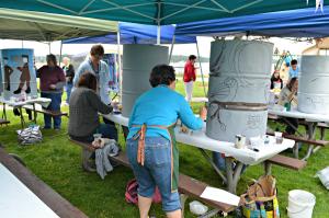 People painting artwork on grey trash cans