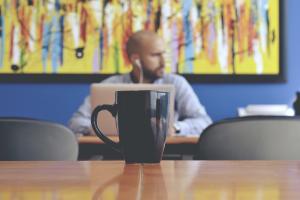 Cup of coffee with man and artwork in background