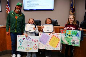 Mayor standing with student participants holding their posters 