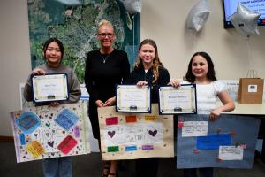 Winners of the 2025 If I Were Mayor contest lined up next to Mayor Massey holding their poster submittals and award certificates