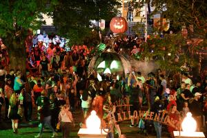 Spirit of Halloweentown pumpkin lighting ceremony with crowd of people and two giant replica pumpkins lit at night 