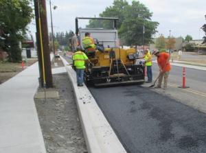 Construction crew working on street paving next to new sidewalks