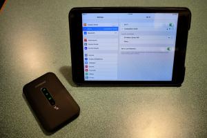 Mobile hotspot sitting next to connected tablet device 