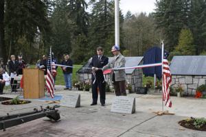 Ribbon cutting ceremony at Veterans Memorial with US flags and veterans 