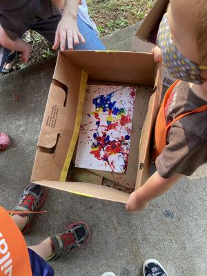 Example outdoor activity of children holding a cardboard box with a paint project inside