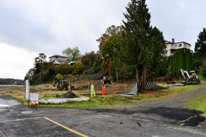 Fence removal along riverfront property with public works crew and machinery around site. 