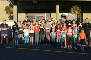 Group photo of kids and police with pizza citations 