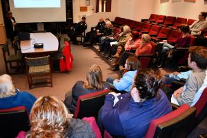 People sit in auditorium with presenter at front of room 
