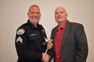 Sgt. Evin Eustice poses with employee of the year award while shaking SHPD Chief Brian Greenway's hand