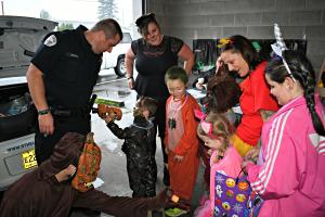St. Helens officer interacting with crowd of trunk-or-treaters at Halloween event. 