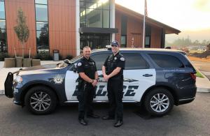 St. Helens School Resource Officers standing in front of police vehicle with school in background