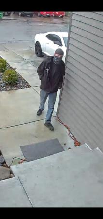 Screen capture of front door security video of package thief walking up to front door