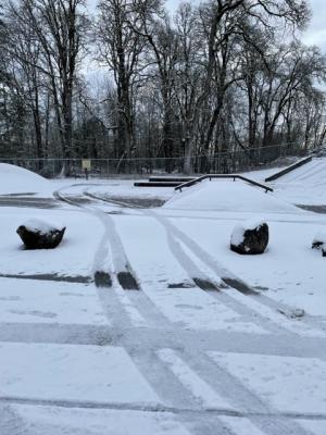 Tire tracks in the snow driving off the road and onto the St. Helens Skate Park 