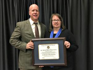 Police Chief Terry Moss and Police Support Specialist Malinda Duran stand together holding an accreditation plaque