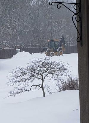 Public Works uses a backhoe to clear snow to the side of the road off Pitsburg Rd