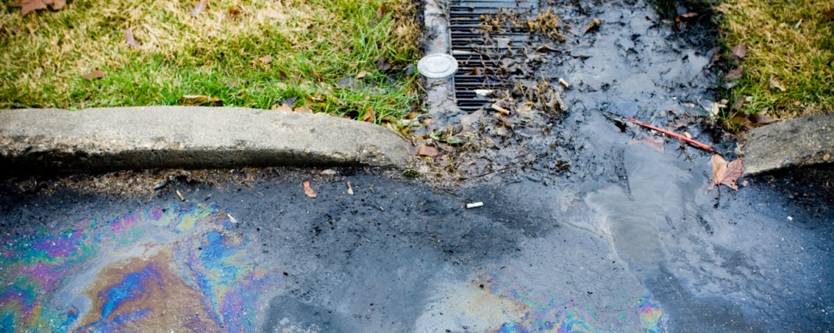 Storm drain with oil sheen from road draining into it